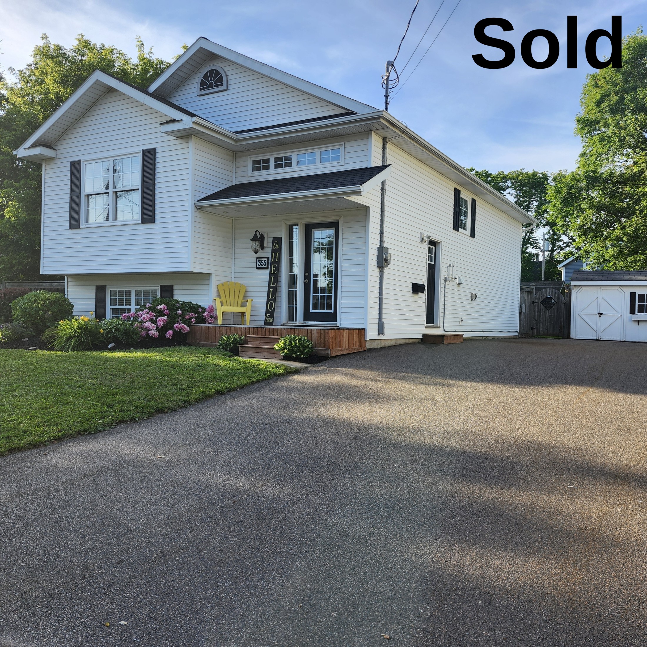A "Sold" photo capturing the exterior of 355 Willow in Summerside, Prince Edward Island, a charming white residential property with a "Hello" sign and manicured landscaping, sold by Jodi Bernard.