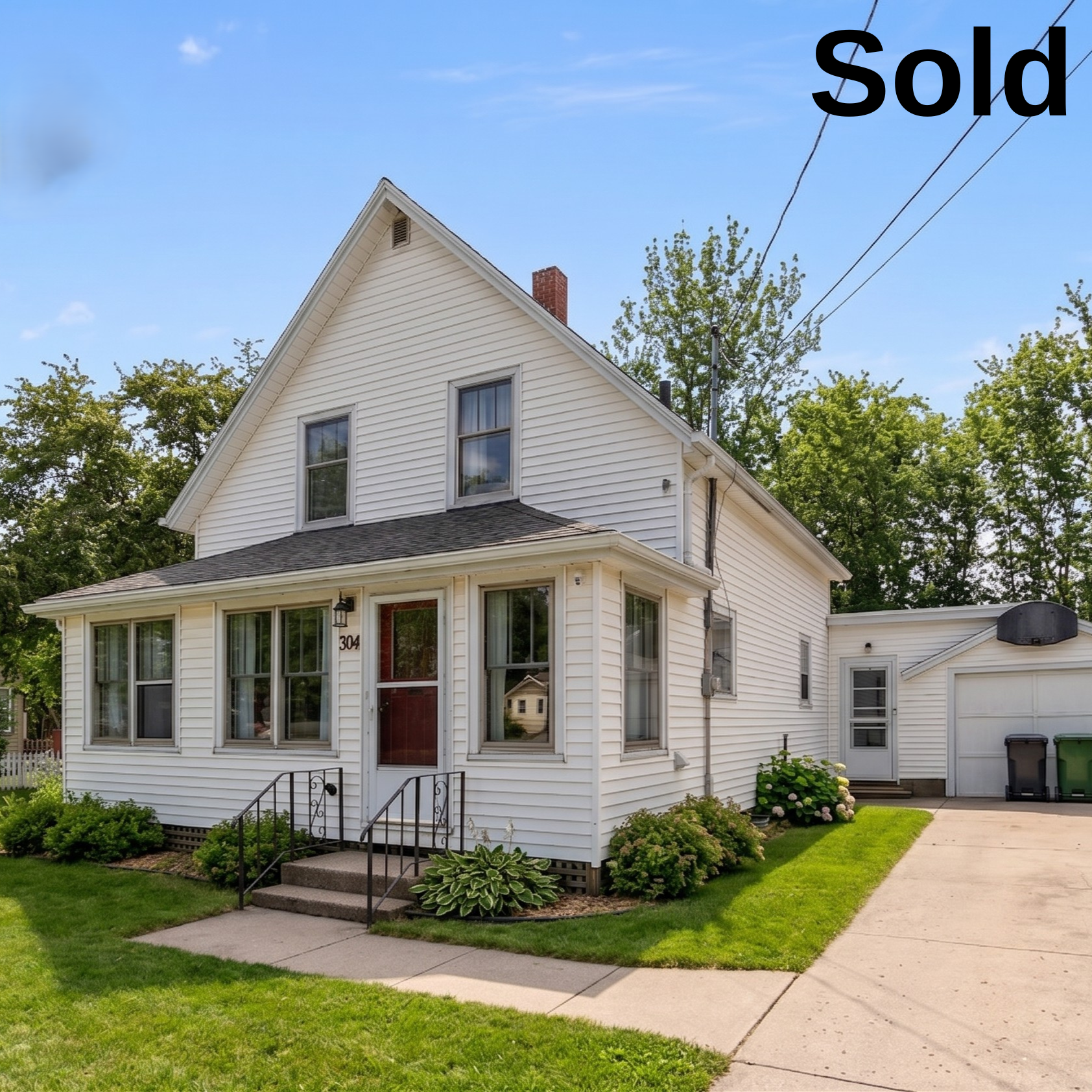 A sold photo of a charming, well-maintained white clapboard character house in Summerside, Prince Edward Island, featuring a front porch and mature trees on a sunny summer day.