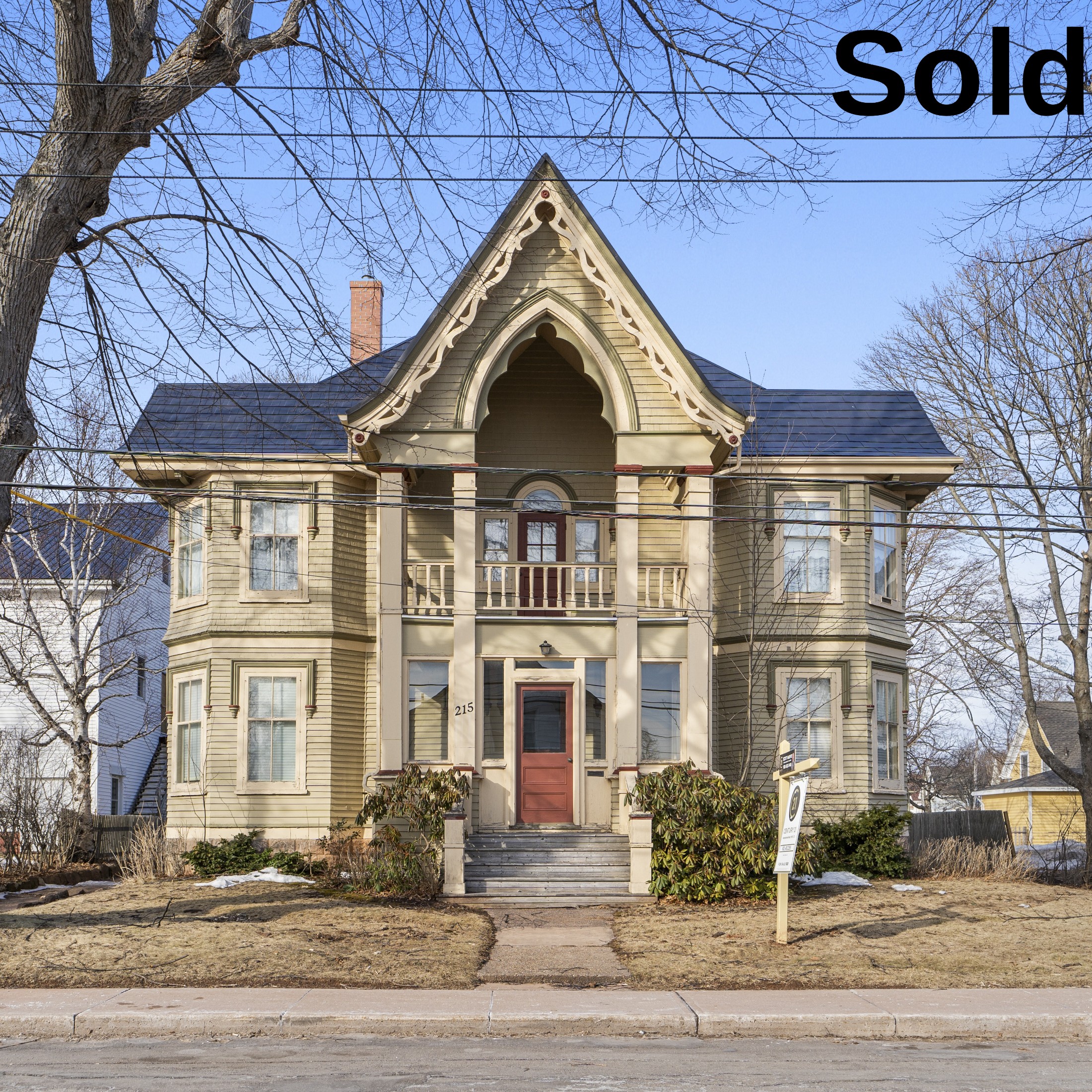 A view of a newly sold, striking Gothic Revival heritage home in Summerside, PEI. The property features an iconic high gabled porch with ornate gingerbread trim, detailed columns, and distinct historical symmetry, sold by Summerside REALTOR® Jodi Bernard.